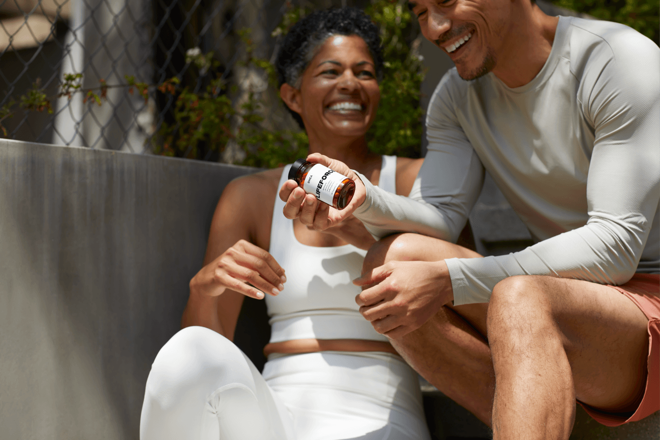 COUPLE LAUGHING AND HOLDING DHEA BOTTLE