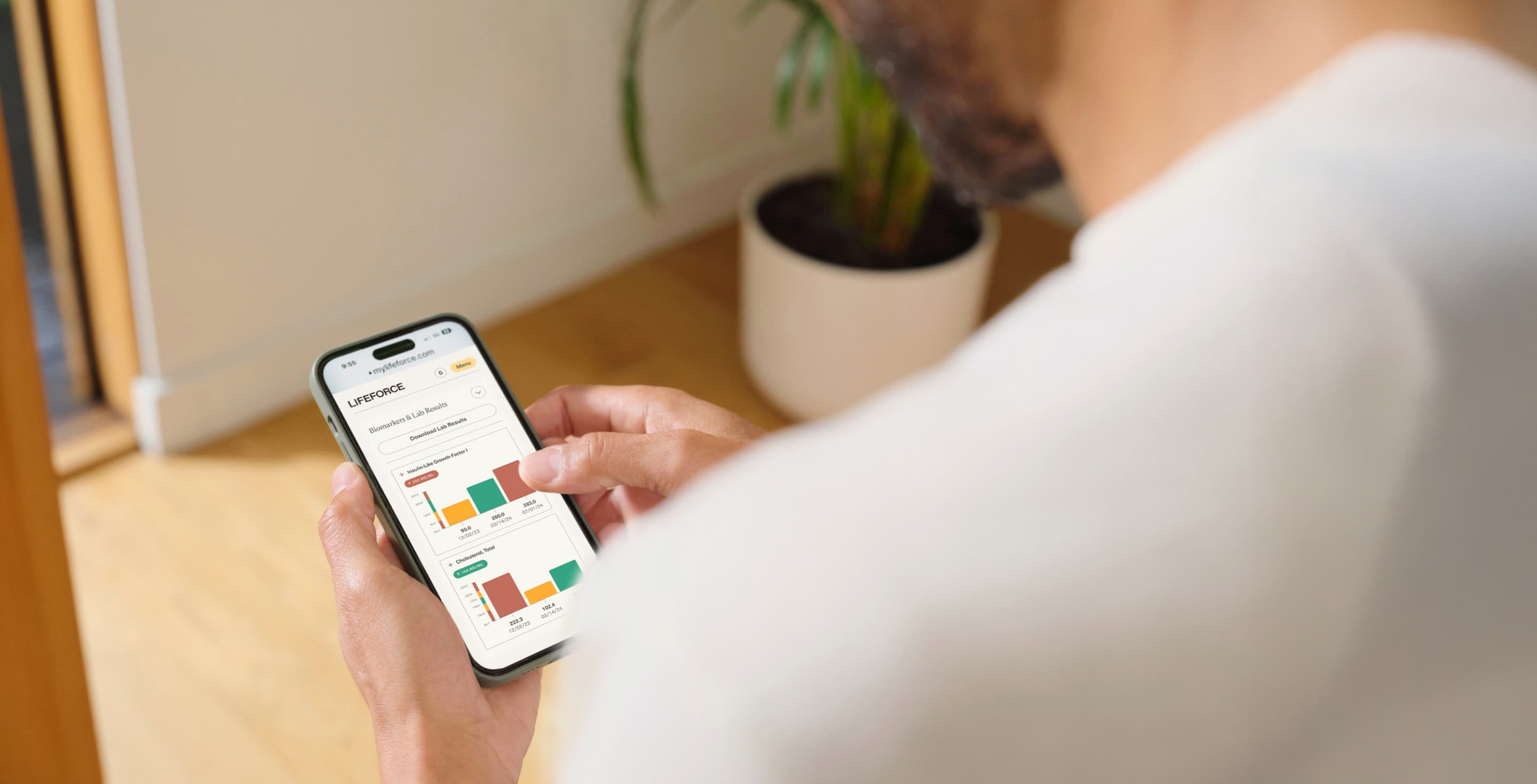 Man holds his mobile phone viewing a dashboard that shows his blood draw results