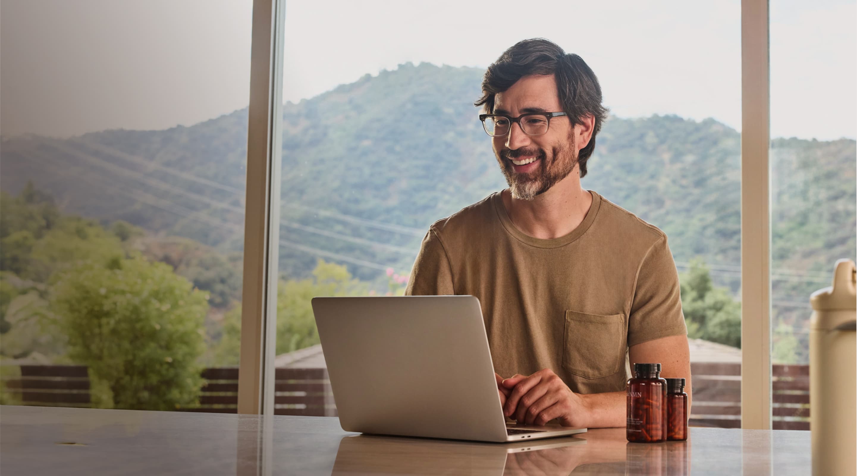 A middle aged man sits at the counter with his laptop